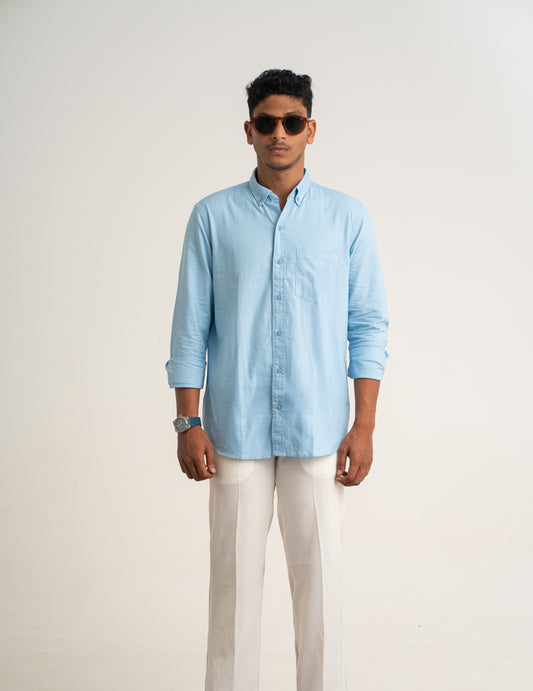 Man wearing a light blue shirt and white pants on a plain background